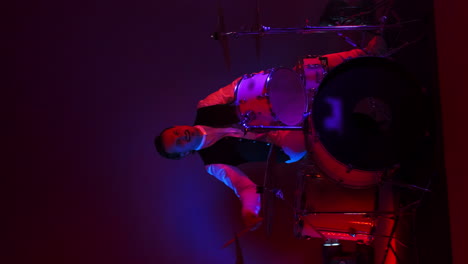 Vertical-video-bright-neon-light-a-male-drummer-plays-in-a-Studio-in-neon-light-and-smoke